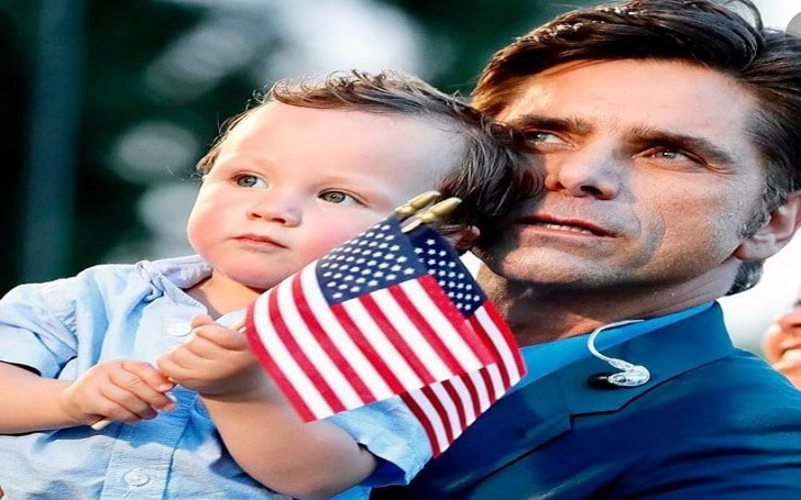 Billy Stamos holding flag of the USA in a blue shirt.